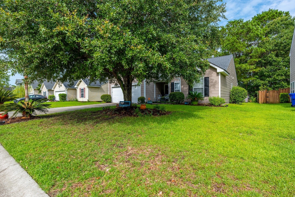 view of property hidden behind natural elements featuring a garage and a front lawn