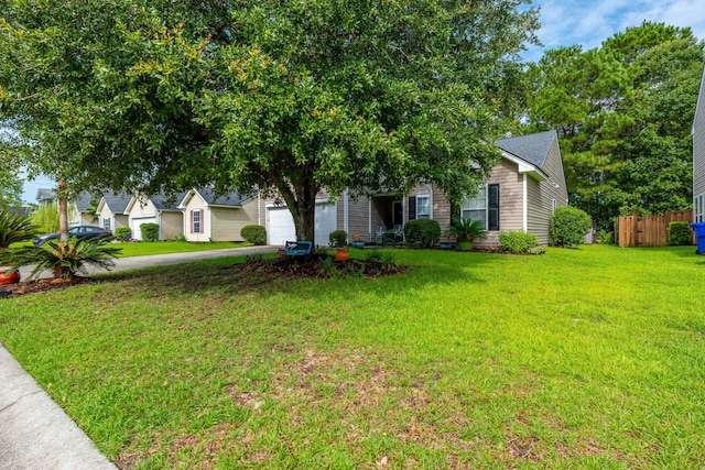 view of property hidden behind natural elements featuring a garage and a front lawn