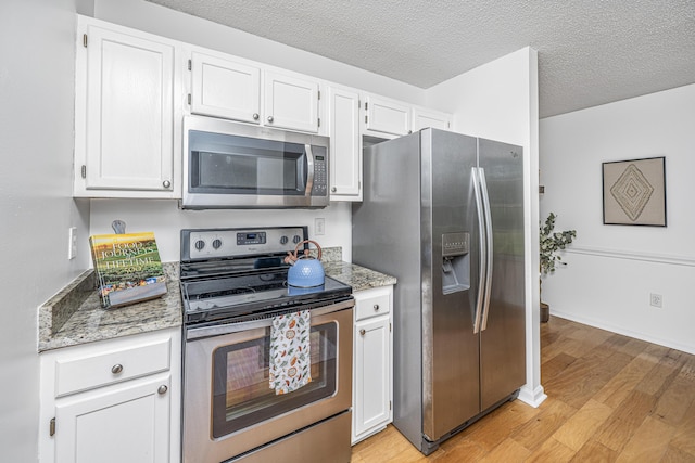 1918 Piper Dr, Charleston, SC 29407 - kitchen featuring stainless steel appliances, light wood-type flooring, white cabinets, light stone counters, and a textured ceiling