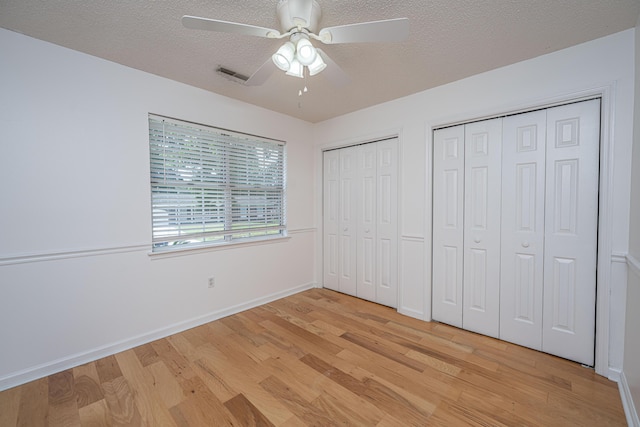 1918 Piper Dr, Charleston, SC 29407 - unfurnished bedroom featuring two closets, light wood-type flooring, baseboards, a textured ceiling, and a ceiling fan