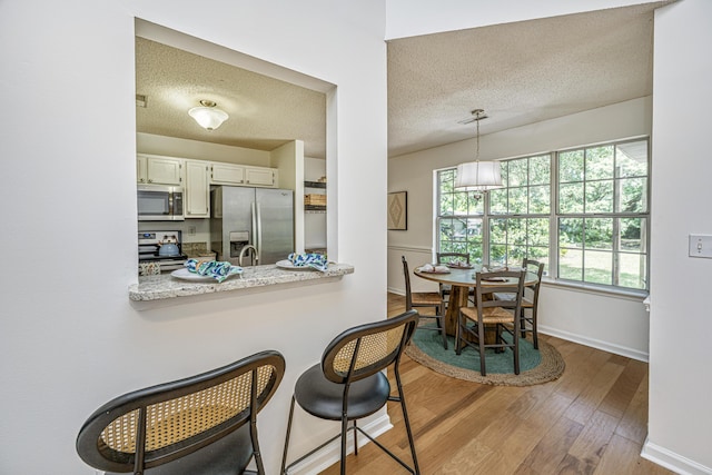 1918 Piper Dr, Charleston, SC 29407 - kitchen with stainless steel appliances, wood finished floors, a textured ceiling, baseboards, and a peninsula