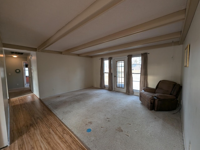 empty room featuring beamed ceiling and light wood-type flooring