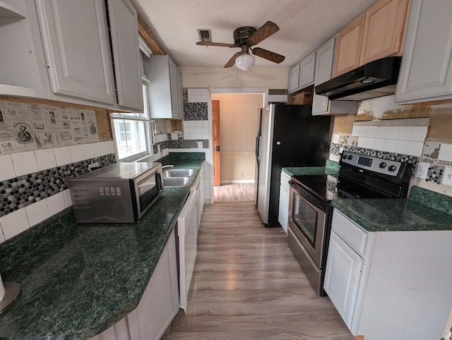 kitchen featuring white cabinets, light wood-type flooring, appliances with stainless steel finishes, and tasteful backsplash