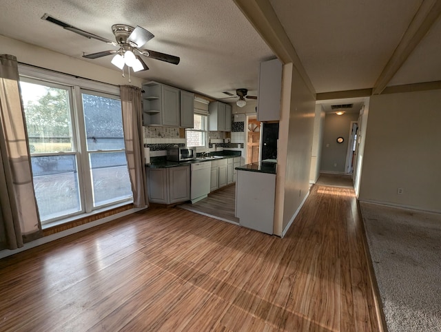 kitchen with ceiling fan, dark hardwood / wood-style flooring, backsplash, white dishwasher, and a textured ceiling