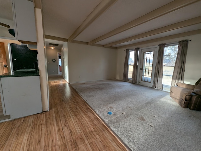 unfurnished living room featuring beam ceiling, light wood-type flooring, and sink