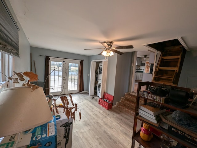 misc room featuring ceiling fan, light hardwood / wood-style floors, stacked washing maching and dryer, and french doors