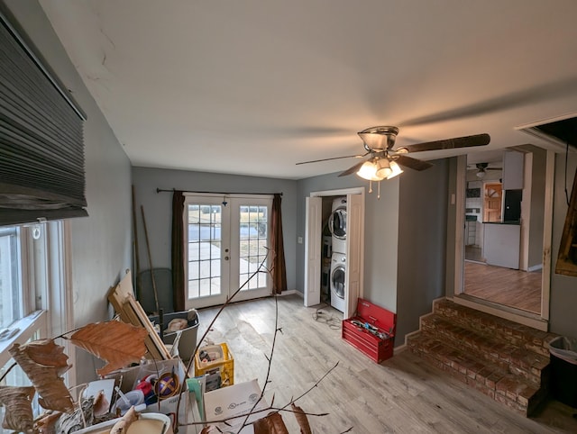 interior space with french doors, light wood-type flooring, stacked washer and dryer, and ceiling fan