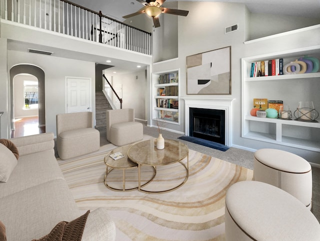 living area with built in features, arched walkways, visible vents, and a fireplace