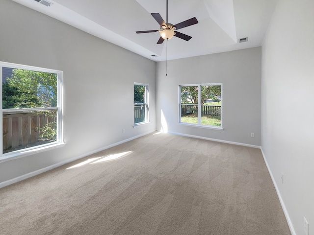 unfurnished room featuring ceiling fan, light colored carpet, and plenty of natural light