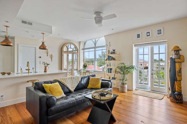 living room featuring baseboards, visible vents, wood-type flooring, and ceiling fan