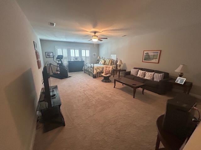 carpeted living area featuring visible vents and a ceiling fan