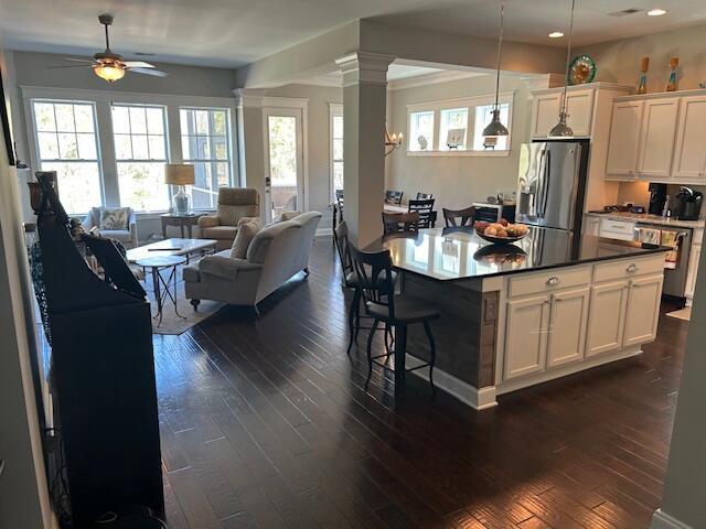 kitchen featuring stainless steel fridge, dishwasher, decorative columns, a ceiling fan, and dark wood-style floors