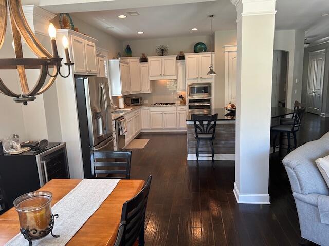 kitchen with dark wood-style flooring, white cabinetry, backsplash, and appliances with stainless steel finishes