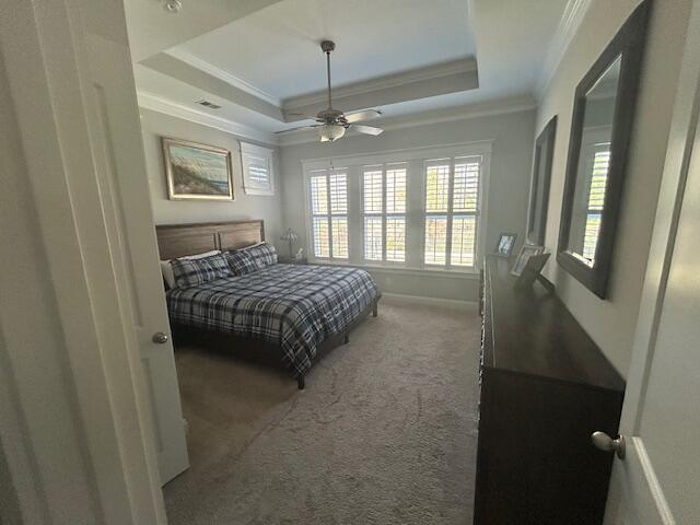 bedroom featuring baseboards, ceiling fan, ornamental molding, carpet floors, and a tray ceiling
