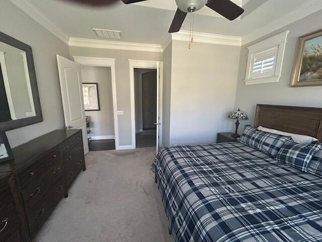 bedroom featuring light colored carpet, visible vents, crown molding, and a ceiling fan