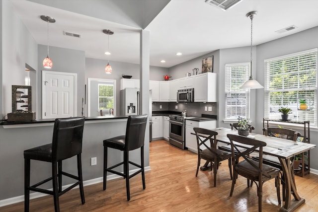 1431 Whispering Oak Trl, Mount Pleasant, SC 29466 - kitchen with stainless steel appliances, dark countertops, light wood finished floors, white cabinets, and a peninsula
