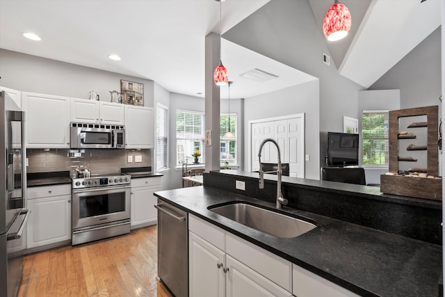 1431 Whispering Oak Trl, Mount Pleasant, SC 29466 - kitchen with stainless steel appliances, light wood-style flooring, dark countertops, white cabinets, and tasteful backsplash