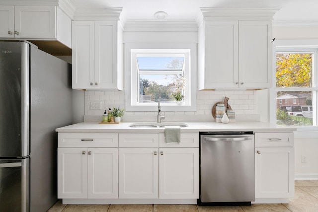 kitchen with tasteful backsplash, sink, white cabinets, and appliances with stainless steel finishes