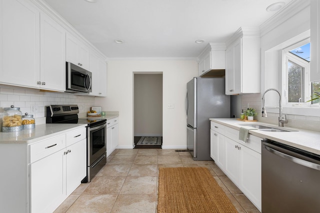 kitchen with decorative backsplash, ornamental molding, stainless steel appliances, sink, and white cabinetry