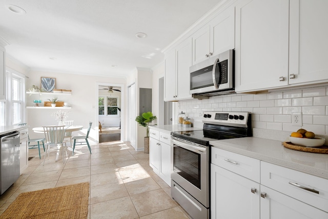 kitchen with white cabinetry, appliances with stainless steel finishes, decorative backsplash, light tile patterned flooring, and ornamental molding