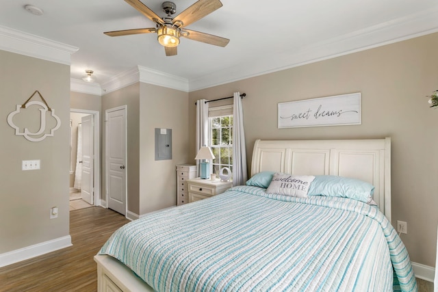 bedroom with ornamental molding, wood finished floors, electric panel, and baseboards