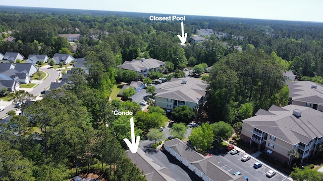 drone / aerial view featuring a wooded view and a residential view