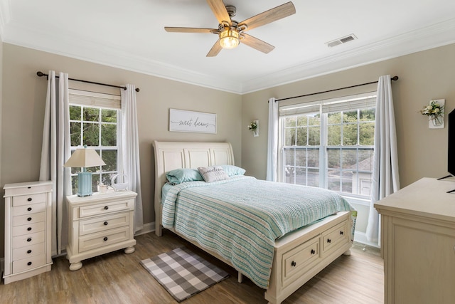 bedroom featuring baseboards, visible vents, ceiling fan, ornamental molding, and light wood-style floors