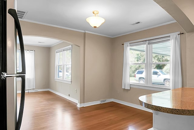 unfurnished dining area featuring crown molding and light hardwood / wood-style flooring