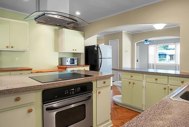 kitchen featuring island exhaust hood, appliances with stainless steel finishes, ornamental molding, and light parquet floors