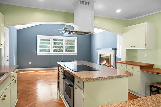 kitchen with island range hood, a center island, black electric cooktop, ceiling fan, and oven