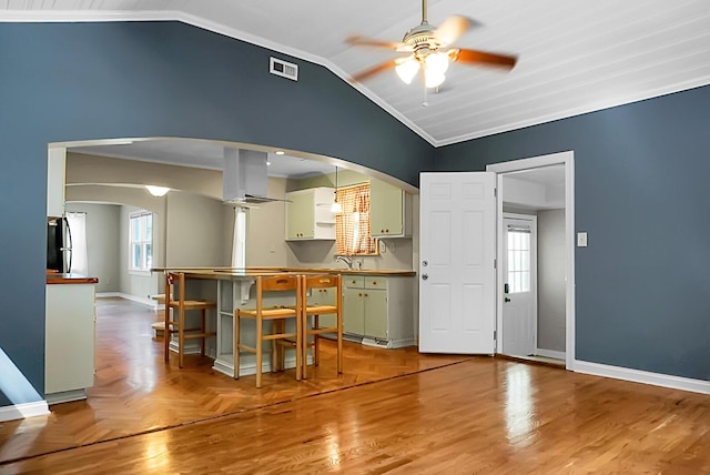 kitchen featuring sink, stainless steel fridge, ceiling fan, range hood, and vaulted ceiling