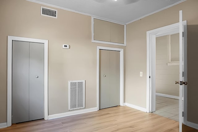 unfurnished bedroom with ornamental molding and light wood-type flooring