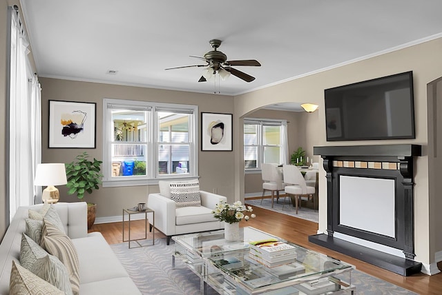 living room with wood-type flooring, ornamental molding, and ceiling fan