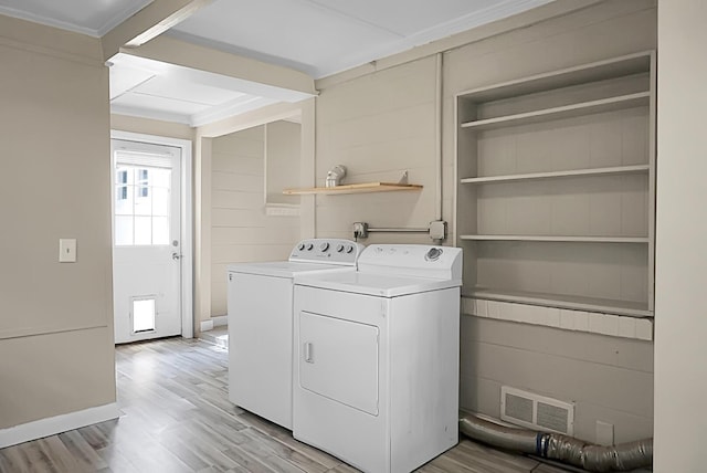 laundry room featuring washing machine and clothes dryer, ornamental molding, and light wood-type flooring