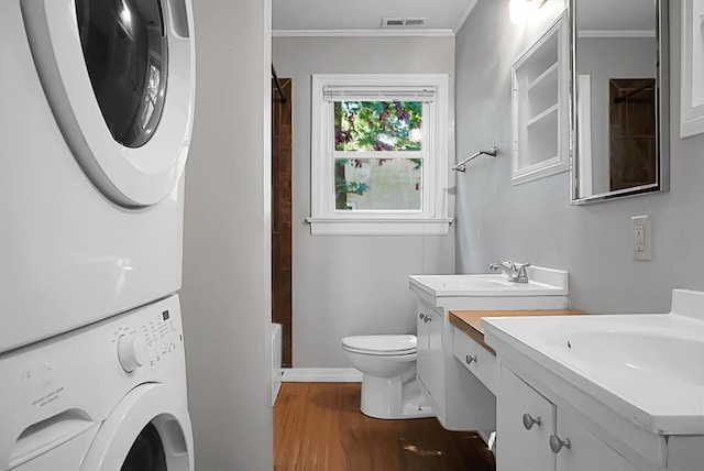 full bathroom with ornamental molding, stacked washer / dryer, toilet, and hardwood / wood-style floors