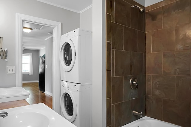 laundry room featuring sink, ornamental molding, hardwood / wood-style floors, and stacked washing maching and dryer