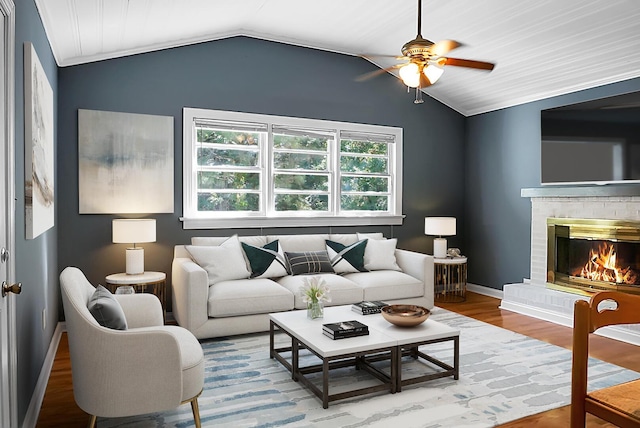 living room with wood-type flooring, vaulted ceiling, ceiling fan, and a fireplace