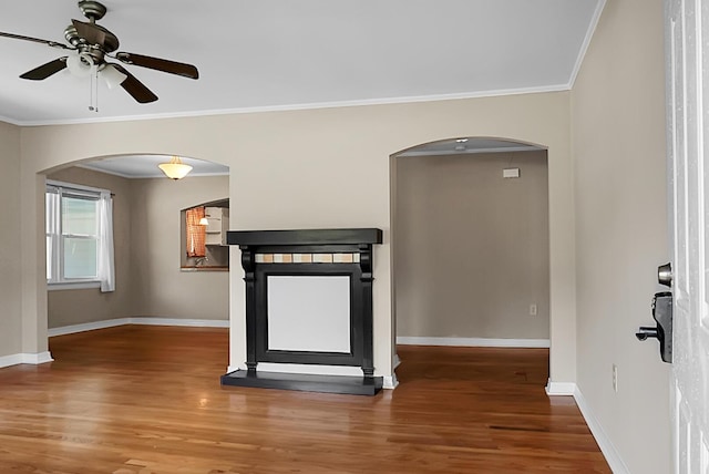 interior space with a fireplace, crown molding, wood-type flooring, and ceiling fan