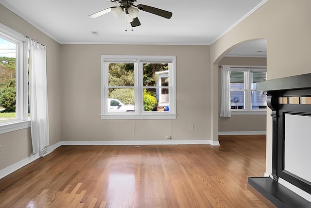 empty room with ornamental molding, a healthy amount of sunlight, and light wood-type flooring