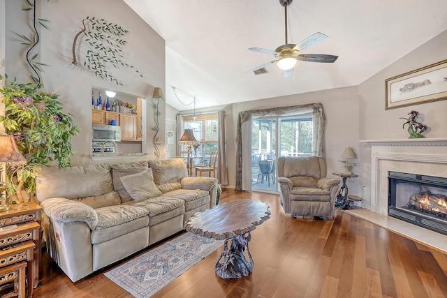 living area with vaulted ceiling, a premium fireplace, wood finished floors, and a textured ceiling