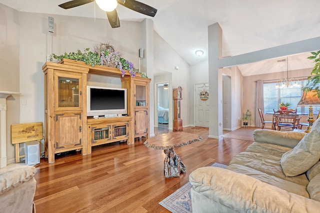 living area featuring baseboards, visible vents, wood finished floors, high vaulted ceiling, and ceiling fan with notable chandelier