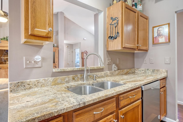 kitchen with light stone counters, brown cabinets, vaulted ceiling, a sink, and dishwasher