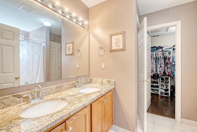 full bath with tile patterned flooring, visible vents, a sink, and a textured ceiling