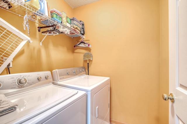 washroom featuring a textured ceiling, laundry area, and washer and clothes dryer