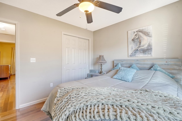 bedroom with a ceiling fan, a closet, baseboards, and wood finished floors