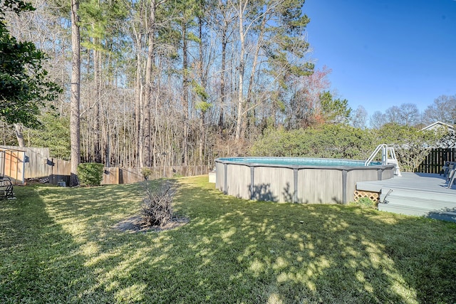 view of yard featuring a deck, fence, and an outdoor pool