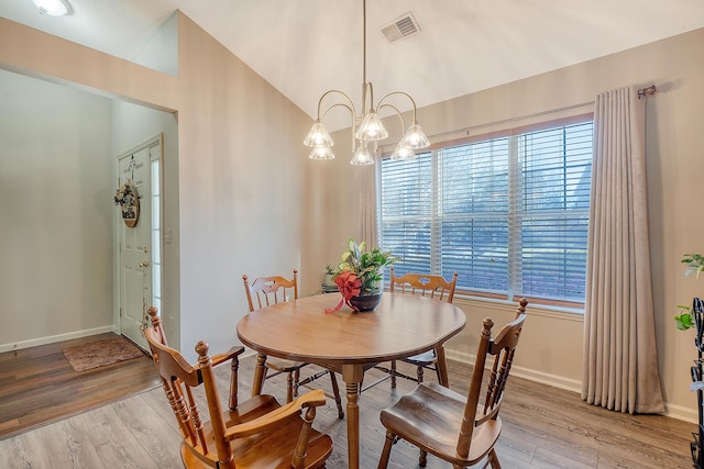 dining room with lofted ceiling, an inviting chandelier, visible vents, and light wood-style floors