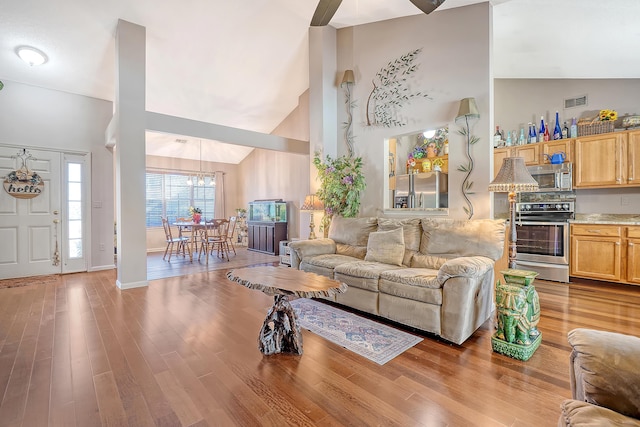 living room featuring high vaulted ceiling, a chandelier, visible vents, and wood finished floors