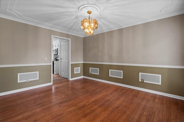 unfurnished room featuring a notable chandelier, wood-type flooring, ornamental molding, and a textured ceiling