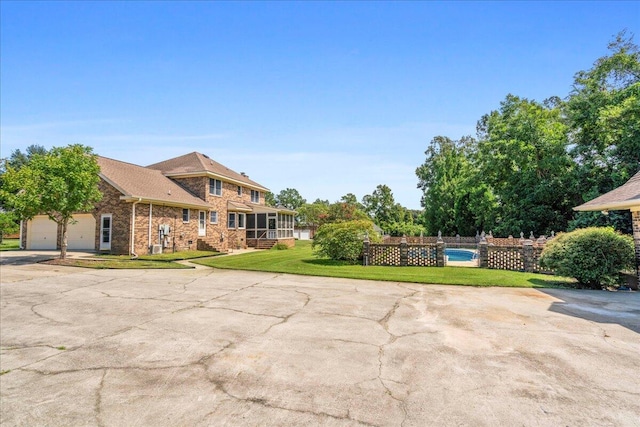 exterior space featuring a front yard, a garage, and a sunroom